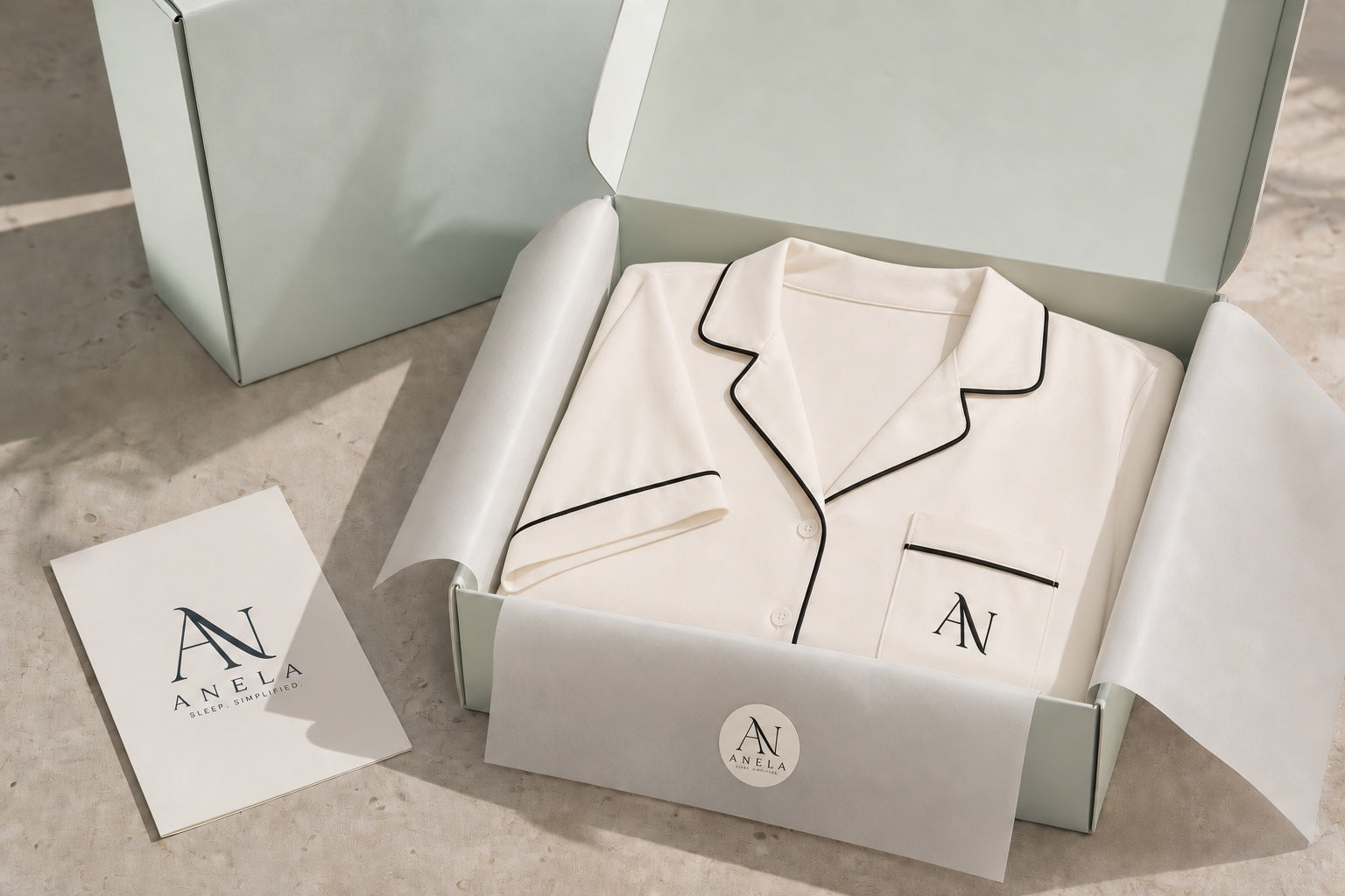 ANELA ivory pyjamas folded beside pale mint paper and an ANELA card